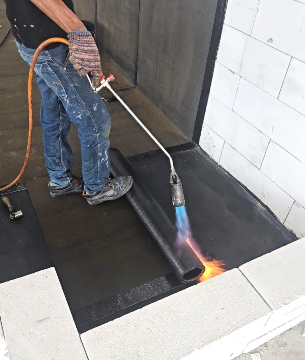 Technician installing torch on waterproof membrane on a Selangor rooftop for Cisco Waterproofing