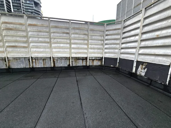 Heat-fused torch-on waterproofing membrane being rolled on concrete surface